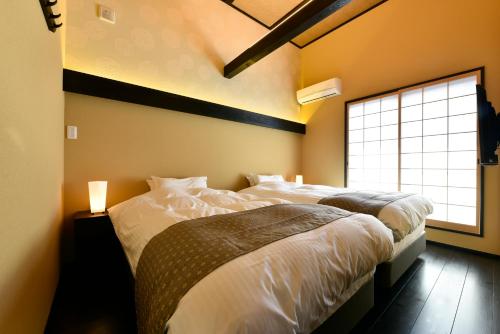 a bedroom with two beds and a window at Miro Hachijo Genmachi BeTei in Kyoto