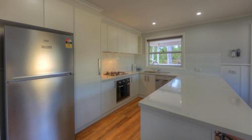 a kitchen with white cabinets and a stainless steel refrigerator at Yarrawonga Holiday Park in Yarrawonga