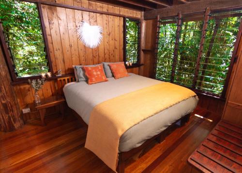 a bedroom with a bed in a room with windows at The Canopy Rainforest Treehouses & Wildlife Sanctuary in Tarzali