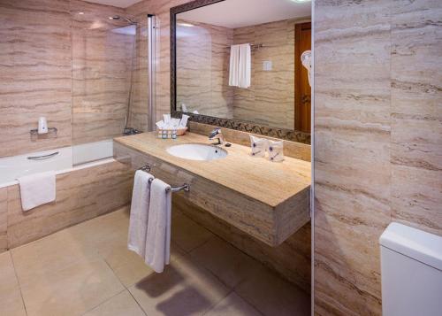 uma casa de banho com um lavatório e um espelho grande em Mediterraneo Bay Hotel & Resort em Roquetas de Mar