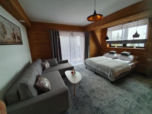 a living room with a couch and a bed at Apartamenty Pod Tatrzańskim Niebem in Zakopane