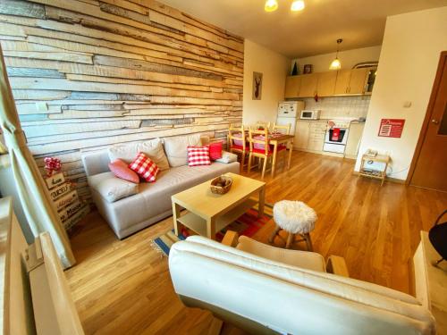 a living room with a couch and a wooden wall at Papa Moose Pamporovo in Pamporovo