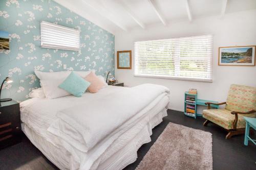 - une chambre avec un lit blanc et une chaise dans l'établissement Annies B and B, à Warkworth