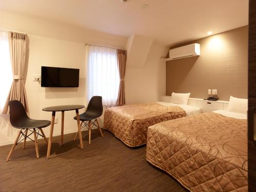 a hotel room with two beds and a table and chairs at Hotel New Tohoku in Tokyo