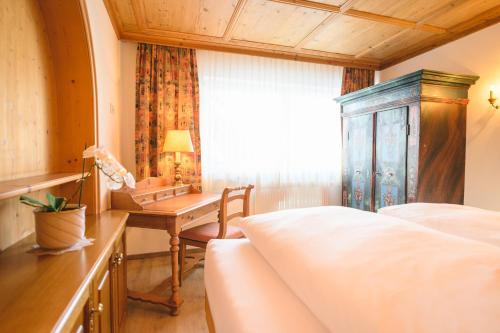 a bedroom with a bed and a desk and a window at Haus Barbarahof in Altenmarkt im Pongau
