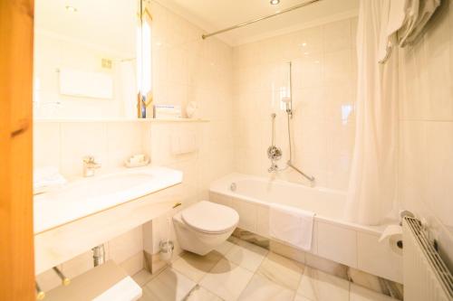 a white bathroom with a toilet and a tub and a sink at Haus Barbarahof in Altenmarkt im Pongau