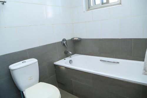 a bathroom with a toilet and a bath tub at Hillview Apartments in Kampala