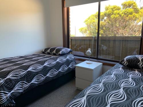 two beds in a room with a window at Beachside House in Kingscote