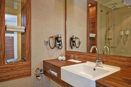 La salle de bains est pourvue d'un lavabo et d'un miroir. dans l'établissement H+ Hotel Lübeck, à Lübeck