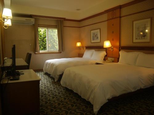 una camera d'albergo con due letti e una televisione di Shan Shui Shen Resortopia Hotel a Guanshan