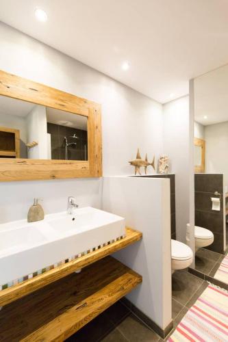 a bathroom with a white sink and a toilet at Zee-en-Zo Noordwijk in Noordwijk