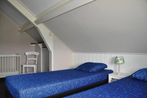 een slaapkamer met 2 bedden met blauwe lakens en een stoel bij Klein Zeeduin in Vrouwenpolder
