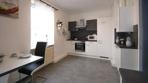 a kitchen with white cabinets and a table and a desk at Haus Renè in Villach