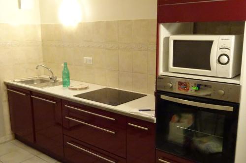 eine Küche mit einer Spüle und einer Mikrowelle in der Unterkunft appart meublé fontanille in Panazol