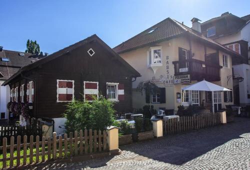 a wooden fence in front of a building with an umbrella at Gasthaus Babsi in Soprabolzano
