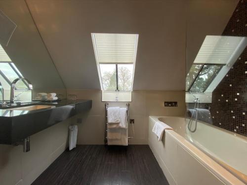a bathroom with a sink and a tub and a window at Great Fosters - Near Windsor in Egham