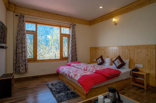 a bedroom with a bed and a large window at Stonehurst Cottage - Mountain-facing Heavenly Abode in Manāli