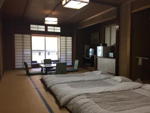 1 dormitorio grande con 2 camas y mesa en Daymaruya Ryokan, en Yamanouchi