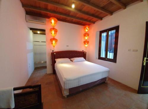 1 dormitorio con 1 cama con luces en la pared en Tiongkok Kecil Heritage Lasem, en Lasem