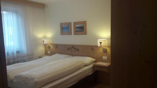 ein Bett in einem Schlafzimmer mit zwei Lichtern an der Wand in der Unterkunft Aliza in Campitello di Fassa