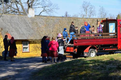 a group of people sitting on the back of a red truck at Kihnu Sadama Öömaja Guesthouse in Lemsi