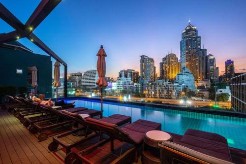 a swimming pool with lounge chairs and a city skyline at Hotel Icon Bangkok Sukhumvit 2 in Bangkok