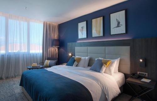 a bedroom with a large bed with blue walls at voco - Podgorica by IHG in Podgorica