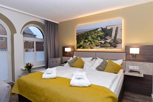 a bedroom with a large bed with towels on it at Hotel Sylter Hof in Westerland