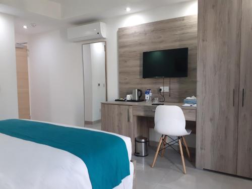 a bedroom with a bed and a desk with a television at TJ Boutique in Marsaskala