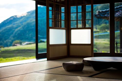 a room with a door and a table and windows at せとうち古民家ステイズHiroshima 不老仙 in Shōbara