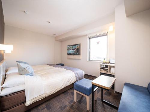 a bedroom with a bed and a desk and a window at Super Hotel Premier Saitama Higashiguchi in Saitama