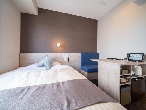 a bedroom with a bed and a desk with a blue chair at Super Hotel Premier Saitama Higashiguchi in Saitama