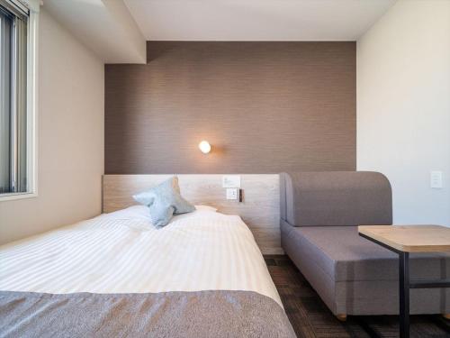 a small bedroom with a bed and a couch at Super Hotel Premier Saitama Higashiguchi in Saitama