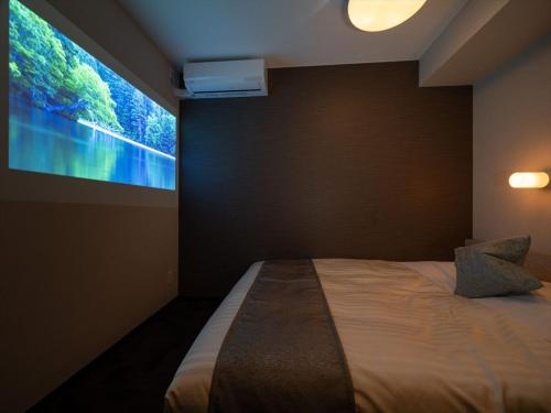 a bedroom with a bed with a large screen at Super Hotel Premier Saitama Higashiguchi in Saitama