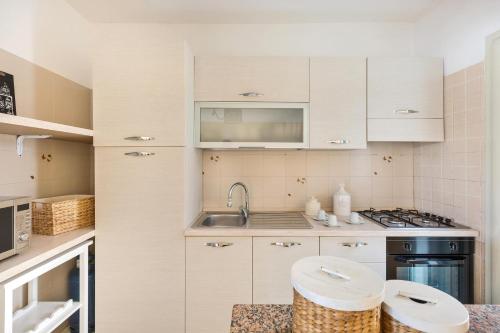 una cucina con armadi bianchi e lavandino di Casa Mya by BarbarHouse a Lido Marini