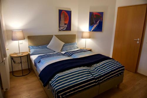 a bedroom with a bed with blue and white striped sheets at Am Strand in Juliusruh