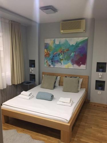 a bedroom with a bed with white sheets and a painting at L9 Top Central Rooms and Apartments 2 in Belgrade