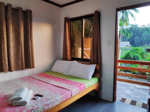 a small bedroom with a bed and a window at NoBi's Inn, Port Barton in San Vicente