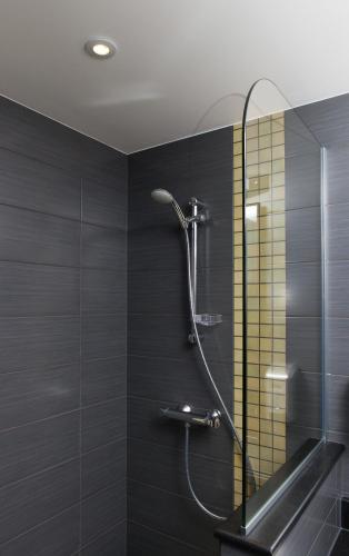 a shower in a bathroom with black tiles at Hotel Restaurant Le Cleebourg in Rott