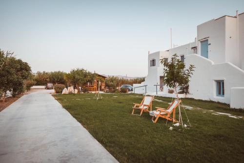 two chairs sitting in the grass next to a building at Annio studios in Plaka