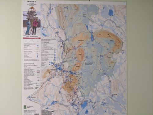 a map hanging on a wall with two people at Tunturioravat in Äkäslompolo