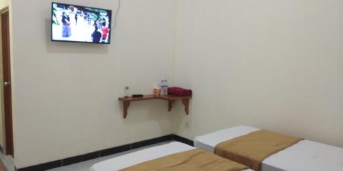 a room with two beds and a tv on the wall at Arrys Watukarung Surfcamp in Kalak