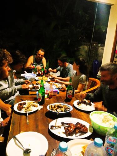 a group of people sitting around a table eating food at Arrys Watukarung Surfcamp in Kalak