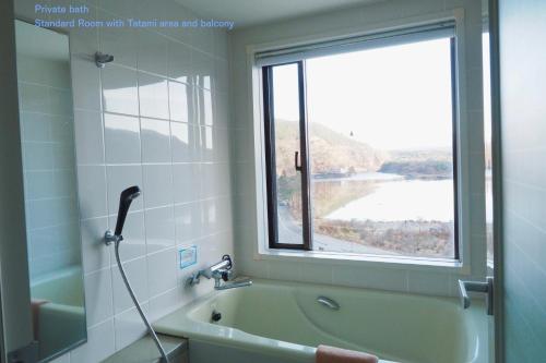 uma casa de banho com uma banheira e uma janela em Shoji Mount Hotel em Fujikawaguchiko