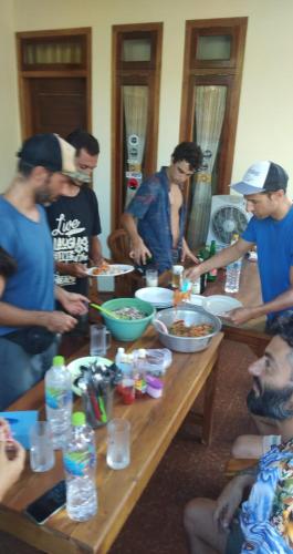 a group of people standing around a table preparing food at Arrys Watukarung Surfcamp in Kalak