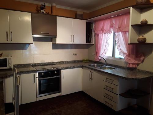 a kitchen with white cabinets and a sink and a window at Ático Andrea in Los Silos
