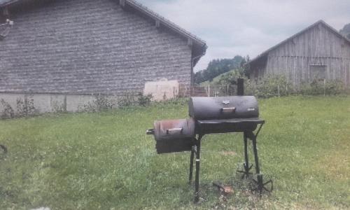 una parrilla de barbacoa en un patio junto a una casa en Ferienhütte Kälberweide, en Hittisau