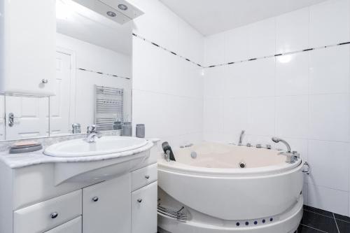 a white bathroom with a tub and a sink at LARGE MODERN HOME, FOUR BEDROOM, TWO BATHROOM in Grays Thurrock