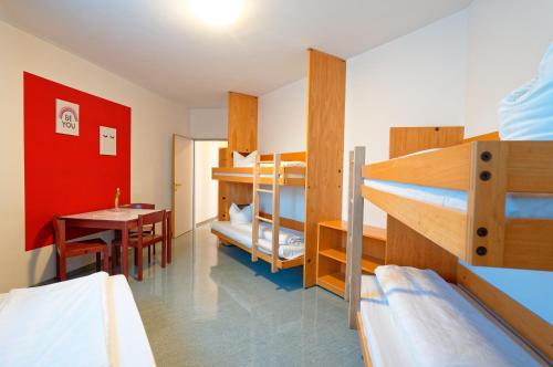 Zimmer mit 3 Etagenbetten, einem Tisch und einem Esszimmer in der Unterkunft Jugend- und Familiengästehaus Klagenfurt in Klagenfurt am Wörthersee