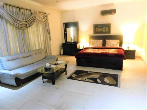 1 dormitorio con cama, sofá y mesa en High Trees Inn, en Islamabad